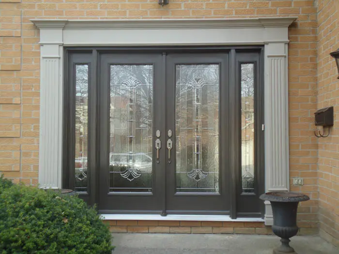 Double front doors with decorative glass panels and white trim set in a classic Markham brick exterior, complemented by a black planter and green shrub nearby.