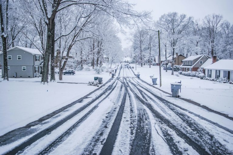 A suburban road covered in snow during a snow storm