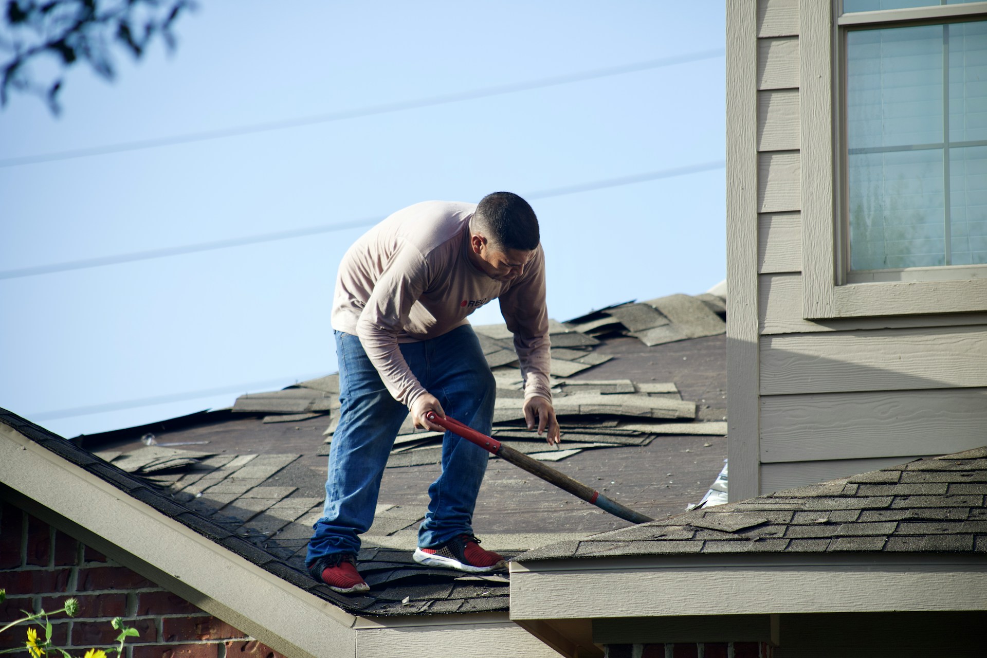 Man tearing off roof shingles