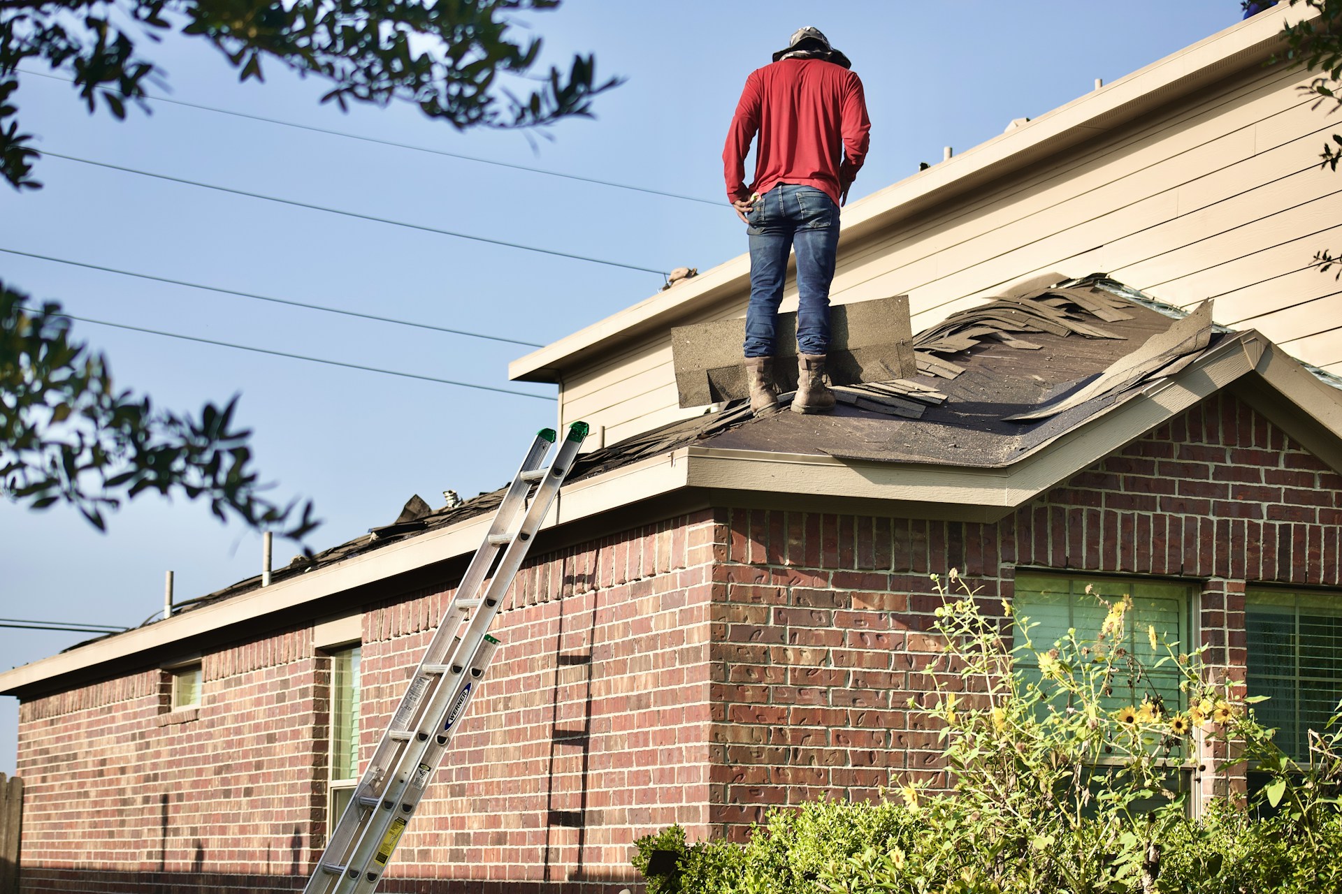 Man standing on a roof inspecting shingles during a repair