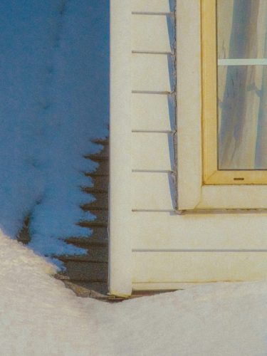 corner of a house showing vinyl siding in winter